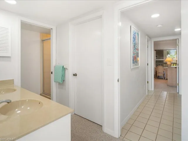 Full bath featuring a shower with door, double vanity, recessed lighting, baseboards, and tile patterned floors