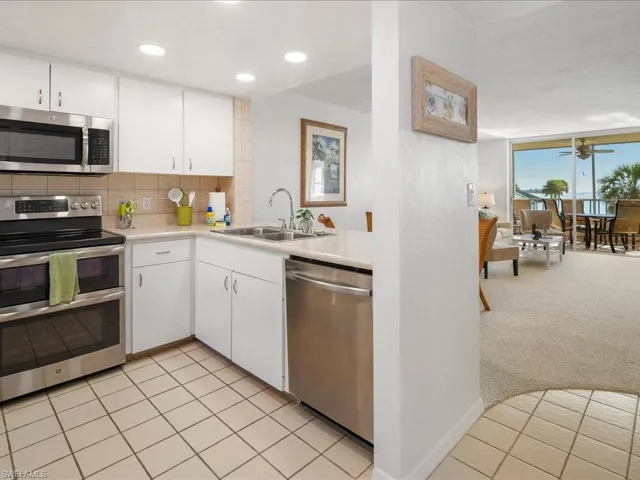 Kitchen with appliances with stainless steel finishes, a sink, light countertops, decorative backsplash, and white cabinets