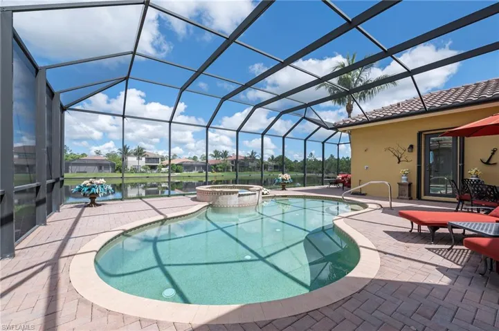 View of swimming pool featuring a patio area, glass enclosure, and an in ground hot tub