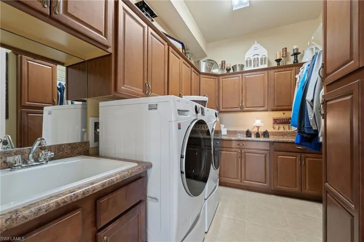 Washroom with sink, light tile floors, and washing machine and clothes dryer