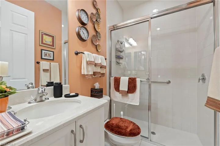 Bathroom with an enclosed shower, oversized vanity, and toilet