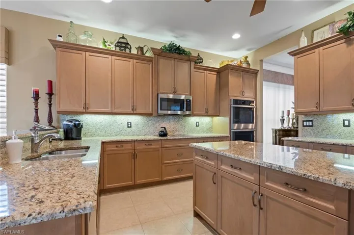 Kitchen featuring ceiling fan, tasteful backsplash, light tile floors, sink, and appliances with stainless steel finishes