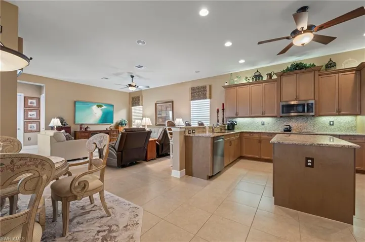 Kitchen featuring appliances with stainless steel finishes, kitchen peninsula, backsplash, and ceiling fan