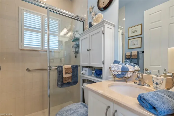 Bathroom featuring walk in shower and vanity with extensive cabinet space