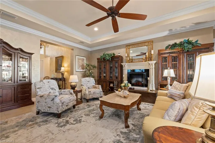 Tiled living room featuring ornamental molding, ceiling fan, and a raised ceiling