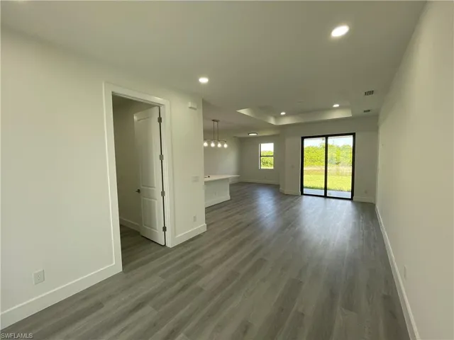 Empty room with recessed lighting, wood finished floors, and a raised ceiling