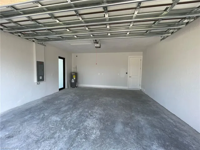 Garage featuring electric panel and electric water heater