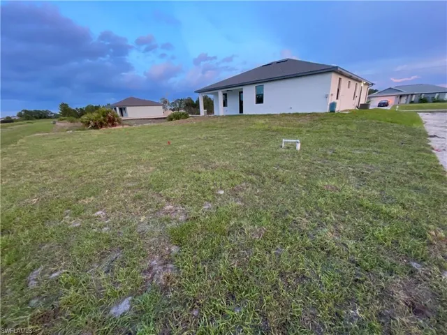 Rear view of property featuring a lawn and stucco siding