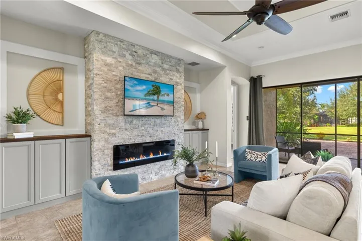Living room featuring ceiling fan, light tile patterned floors, a fireplace, and ornamental molding