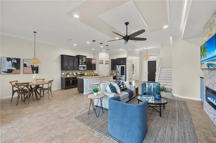Living room featuring light tile patterned flooring, a fireplace, ceiling fan, ornamental molding, and sink