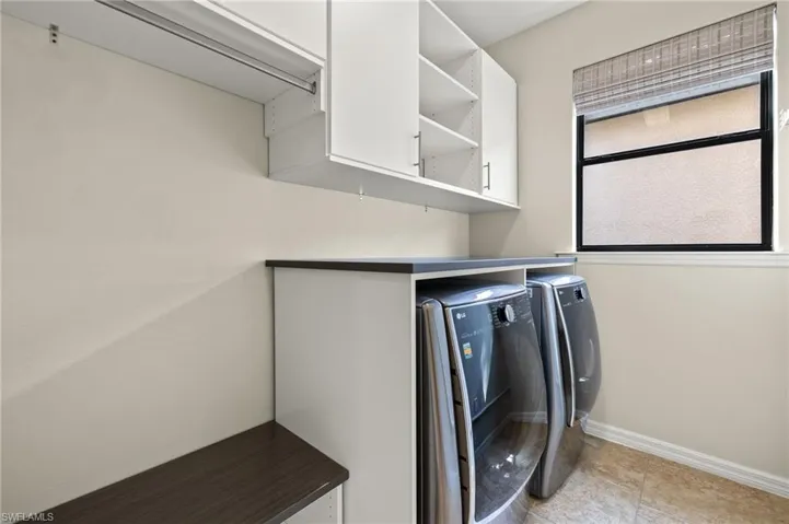Laundry area featuring cabinets, light tile patterned floors, and washing machine and clothes dryer