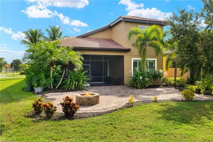 Back of house featuring a fire pit, a sunroom, a yard, and a patio area