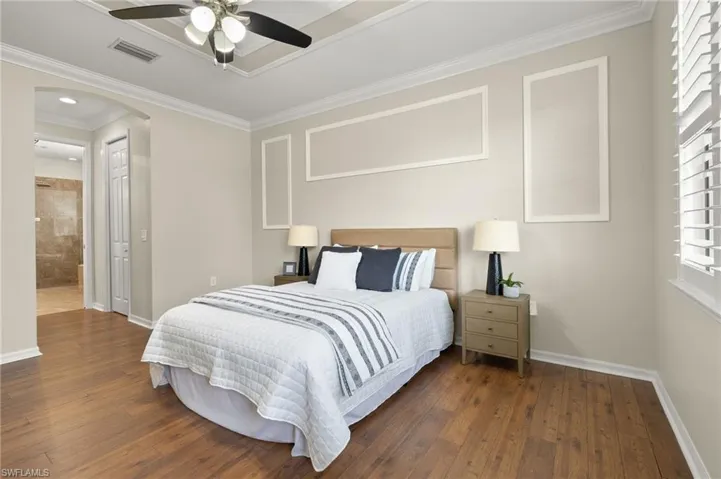 Bedroom featuring ceiling fan, dark hardwood / wood-style floors, ensuite bathroom, and crown molding