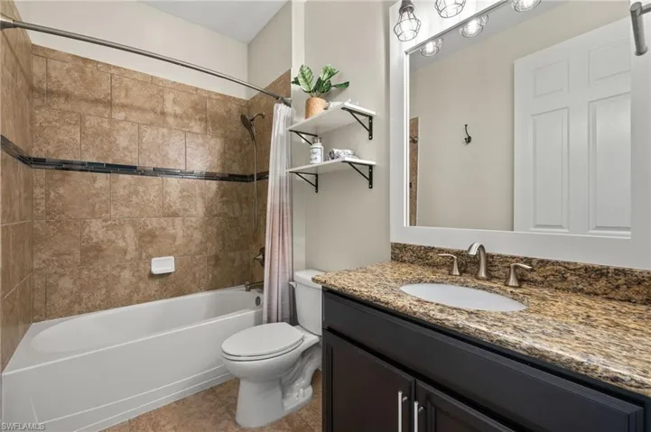 Full bathroom featuring shower / bath combination with curtain, tile patterned flooring, vanity, and toilet