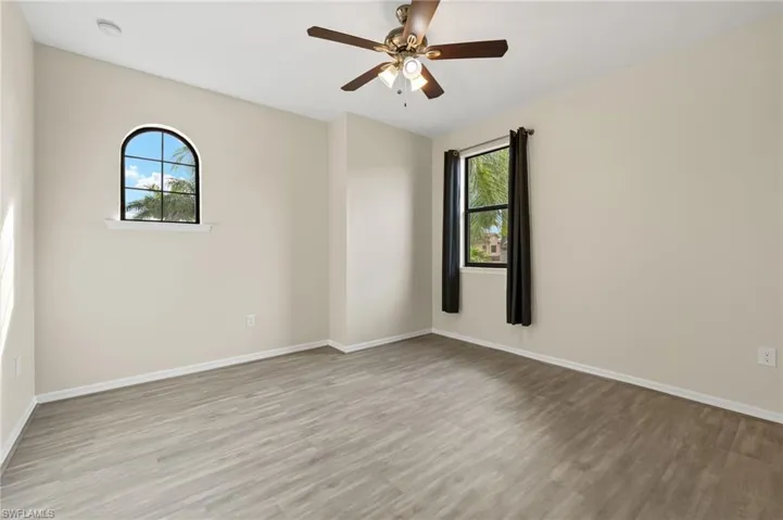 Spare room with light wood-type flooring, ceiling fan, and plenty of natural light