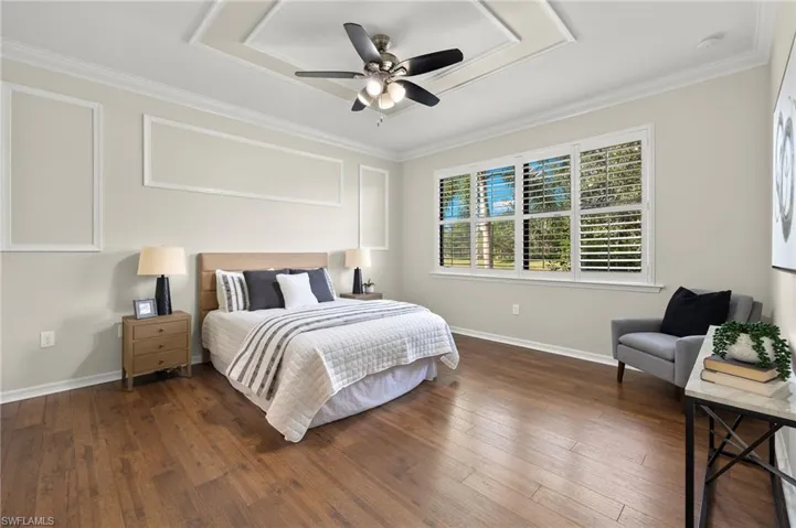 Bedroom featuring ceiling fan, ornamental molding, and dark wood-type flooring