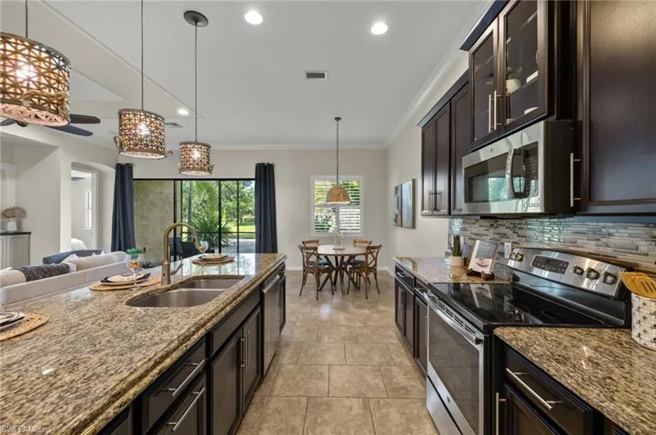 Kitchen featuring dark brown cabinets, light stone counters, appliances with stainless steel finishes, and sink