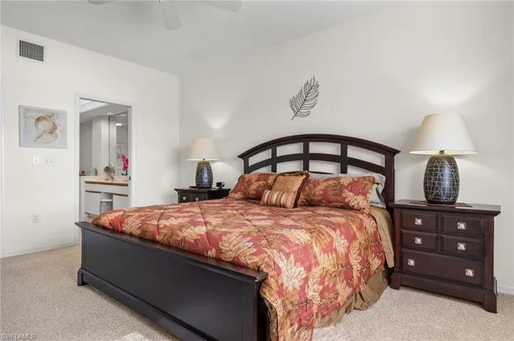 Carpeted bedroom featuring ensuite bath and ceiling fan