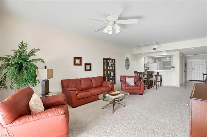 Carpeted living room featuring ceiling fan and rail lighting