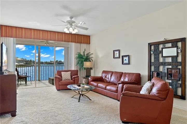 Carpeted living room featuring ceiling fan and a water view