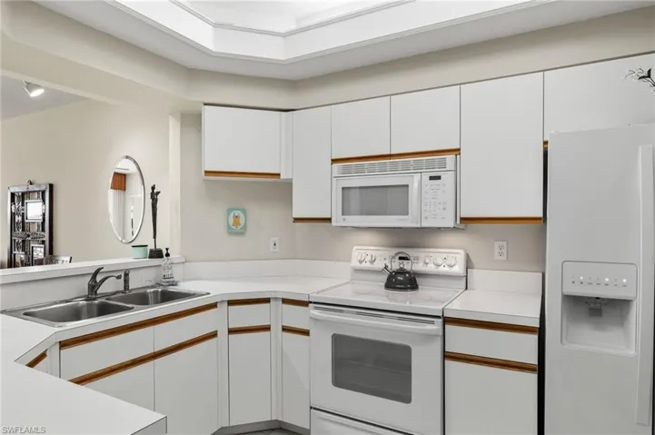 Kitchen with sink, white appliances, and white cabinetry