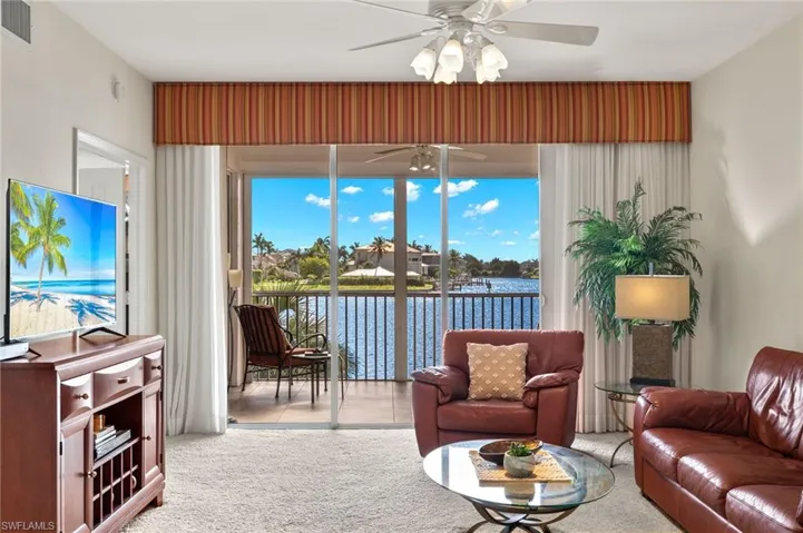 Carpeted living room with ceiling fan, a wealth of natural light, and a water view