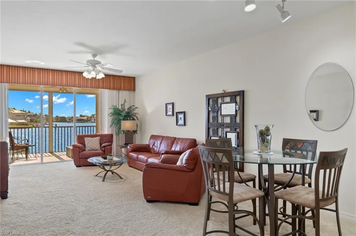 Carpeted living room featuring ceiling fan and a water view