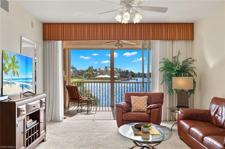 Living room with carpet, ceiling fan, and a water view