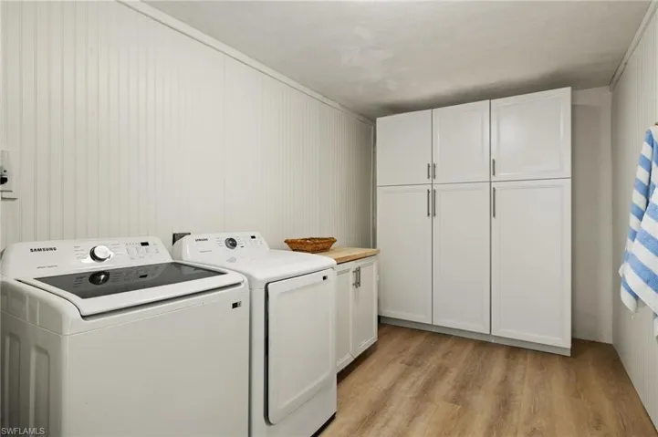 Washroom with light wood-type flooring, cabinet space, and washer and clothes dryer