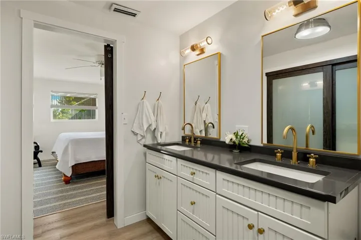 Bathroom featuring double vanity, light wood-type flooring, and ensuite bath