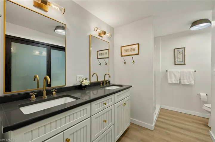 Full bathroom featuring double vanity, light wood-style floors, and walk in shower