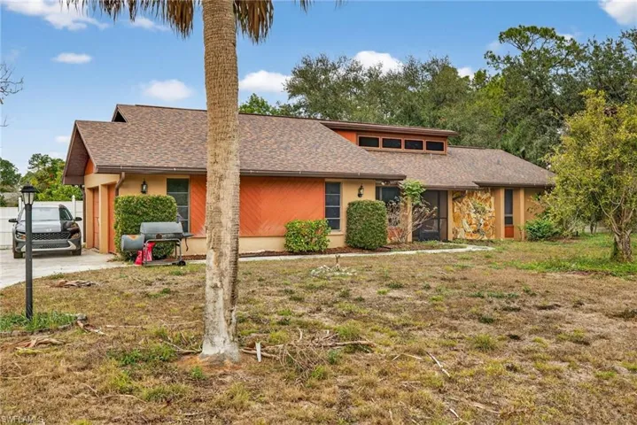 View of front of house featuring roof with shingles, an attached garage, a front lawn, and stucco siding