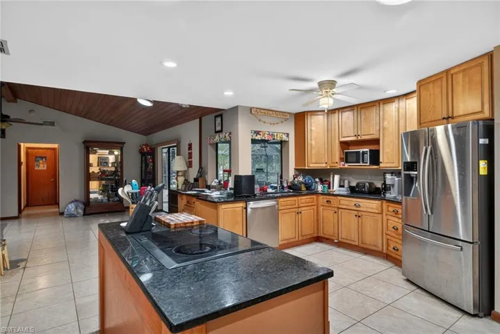 Kitchen with a ceiling fan, stainless steel appliances, wood finish cabinets, a peninsula, and a vaulted wooden ceiling