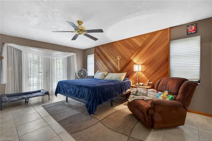 Bedroom featuring wooden walls, a ceiling fan, access to outside, and tile patterned floors