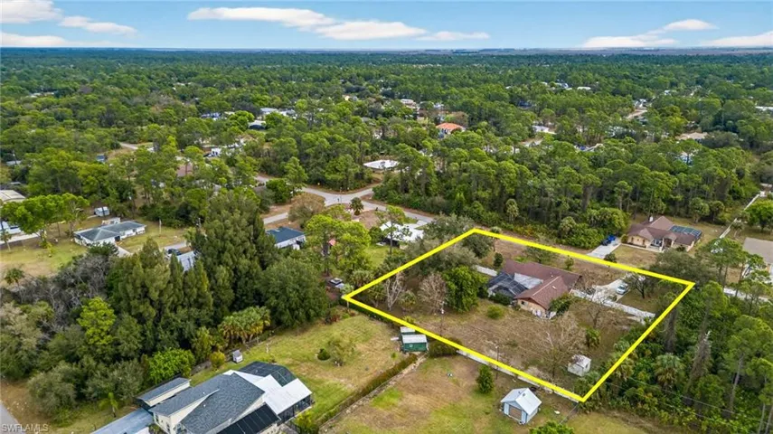 Aerial perspective of suburban area with a heavily wooded area and property parcel outlined