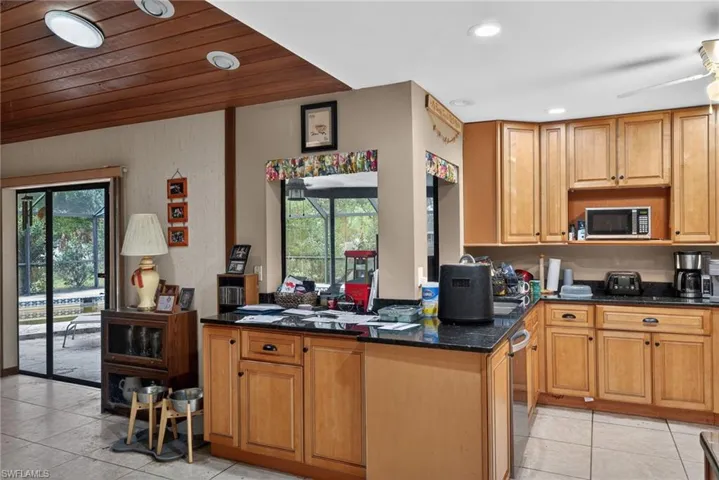 Kitchen featuring wood finish cabinets, dark stone counters, ceiling fan, stainless steel appliances, and recessed lighting