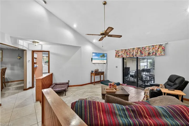 Living area featuring ceiling fan, light tile patterned flooring, vaulted ceiling, and recessed lighting