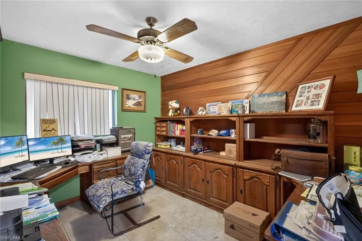 Office area with ceiling fan, wood walls, and light tile patterned flooring