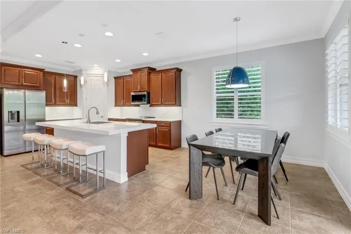 Kitchen featuring tasteful backsplash, hanging light fixtures, a kitchen island with sink, sink, and stainless steel appliances