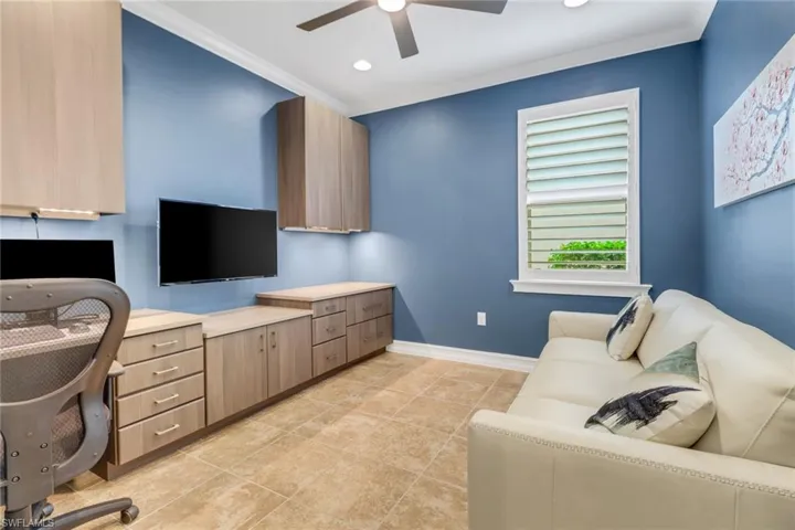 Office space featuring built in desk, crown molding, light tile patterned floors, and ceiling fan