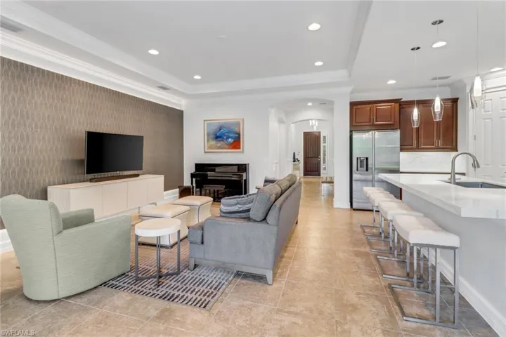 Living room featuring sink, light tile patterned flooring, and crown molding