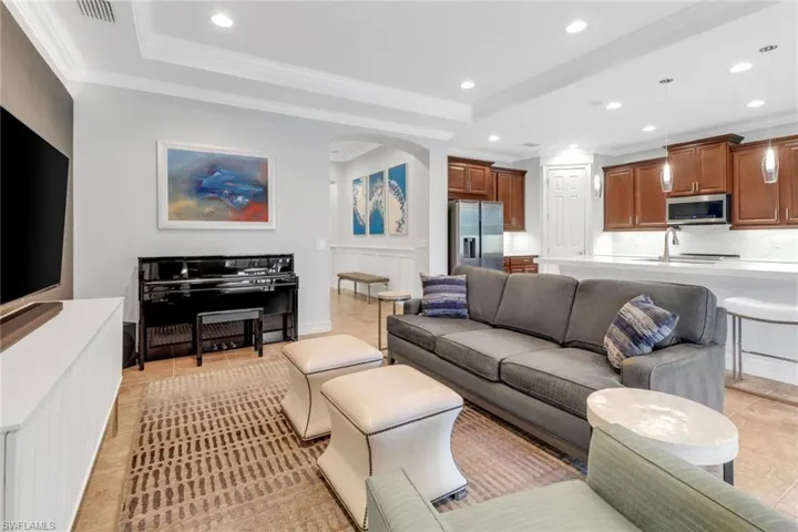 Tiled living room featuring crown molding, a raised ceiling, and sink