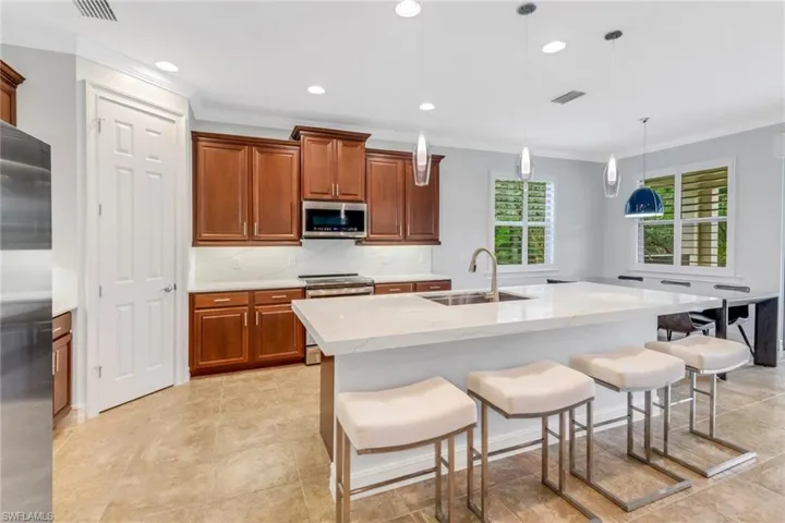 Kitchen with a center island with sink, appliances with stainless steel finishes, a breakfast bar area, and pendant lighting