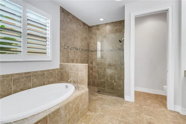 Bathroom featuring toilet, tile patterned floors, and plus walk in shower