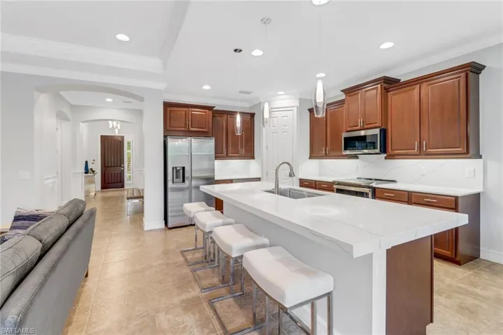 Kitchen featuring sink, decorative backsplash, appliances with stainless steel finishes, and a kitchen island with sink