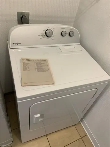Laundry room with washer / clothes dryer, a textured wall, and light tile patterned floors