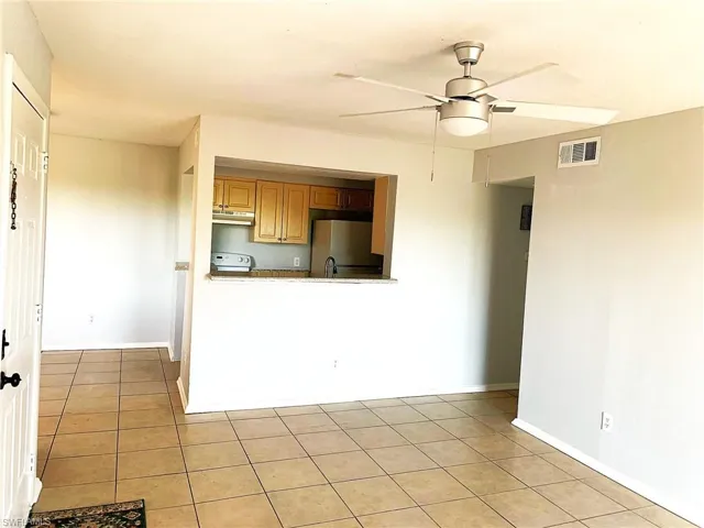 Kitchen featuring freestanding refrigerator, ceiling fan, light tile patterned floors, and white range with electric cooktop