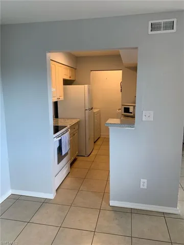 Kitchen with white appliances and light tile patterned floors