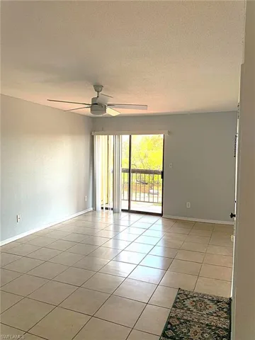 Spare room featuring a textured ceiling, light tile patterned floors, and ceiling fan