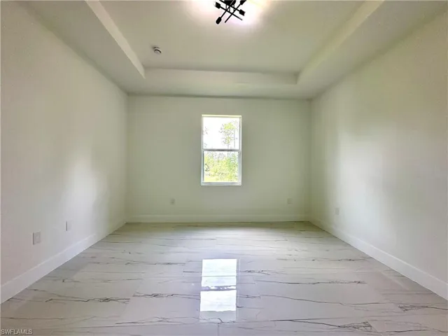 Spare room with light marble finish flooring and a tray ceiling